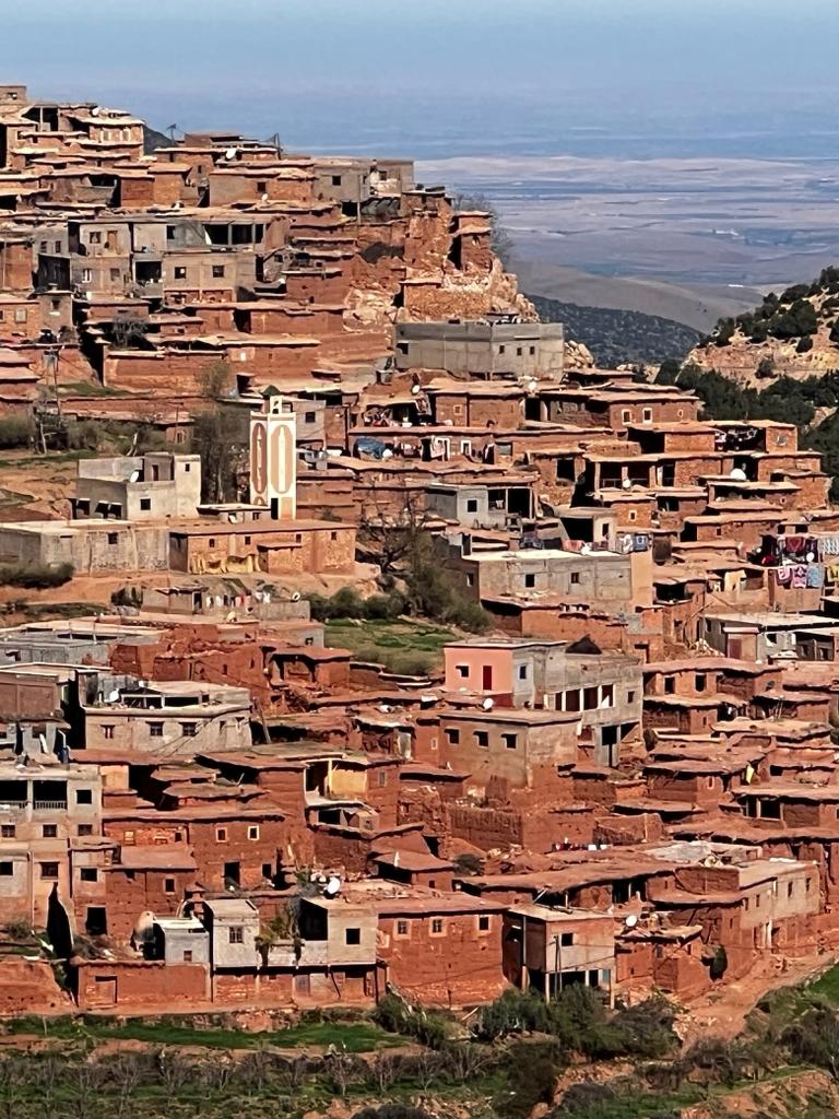 A Berber hillside village of terraced mudbrick houses overlooking a valley.