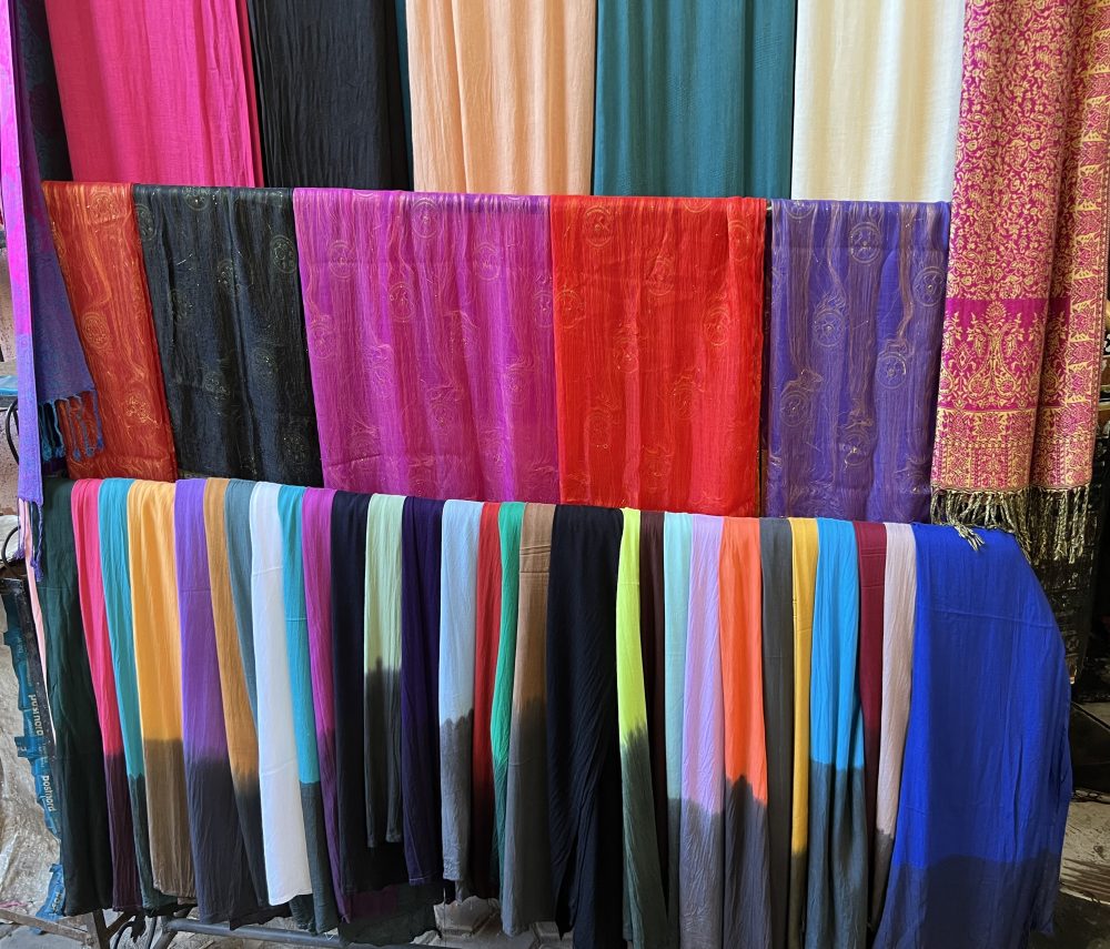 Rows of colourful silk and pashmina scarves hanging for sale at a Marrakech market stall.