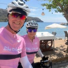 Peter Swensen and Gab Gallagher in Bike Odyssey cycling kit at a waterside cafe on The Odyssey tour